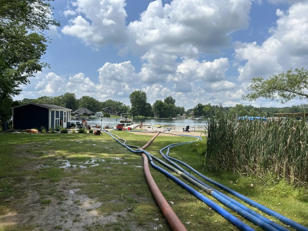 beach sanding and restoration on Long Lake in White Pigeon Michigan. Sandpro hoses are out and workers in the water spreading sand on the new waterside lake bottom beach.